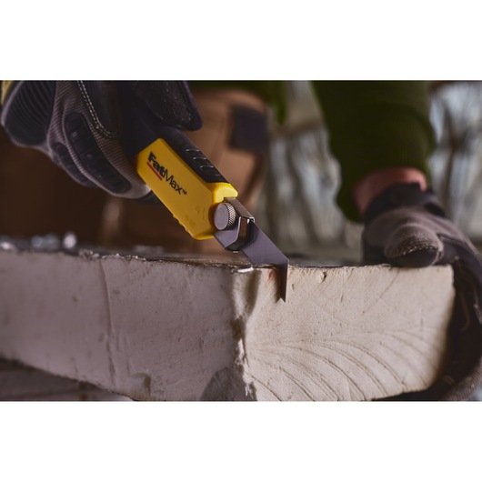STANLEY 0-10-481 utility knife cutting drywall, close-up view with gloved hand using yellow and black tool.