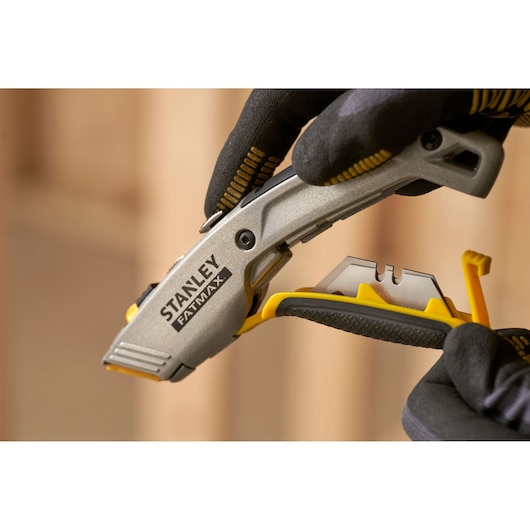 Stanley 0-10-789 utility knife with blade storage, close-up photo showing tool held in gloved hands.