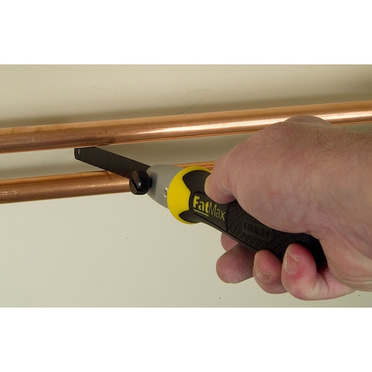 STANLEY 0-20-220 FatMax hand saw cutting copper pipe, close-up photo showing ergonomic handle.