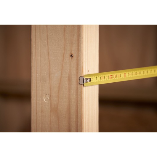 STANLEY 0-32-109 tape measure measuring wooden beam, close-up side angle, photography.