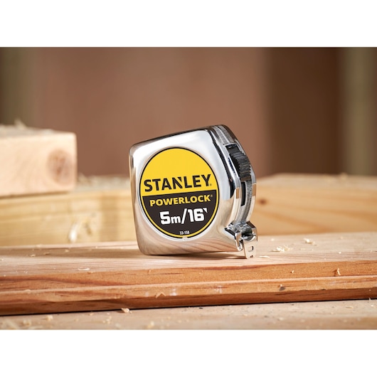 STANLEY 0-33-158 PowerLock tape measure with chrome finish, shown on wooden planks, product front angle.