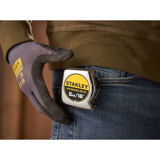 STANLEY 0-33-158 PowerLock tape measure clipped to jeans pocket, gloved hand close-up.