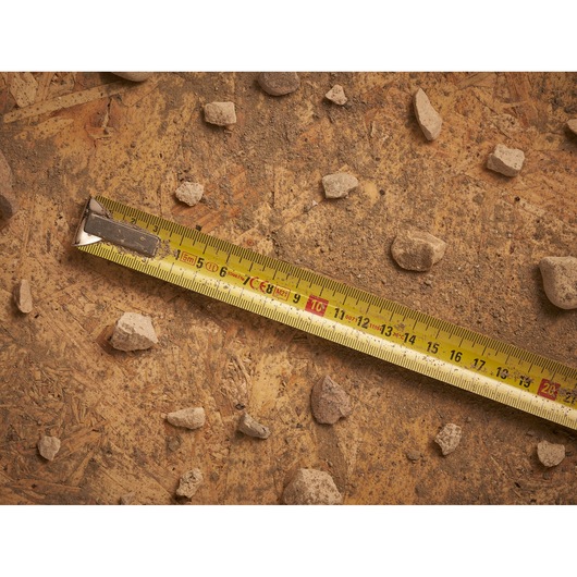 STANLEY 0-33-195 tape measure on rough surface with scattered rocks, photography product.
