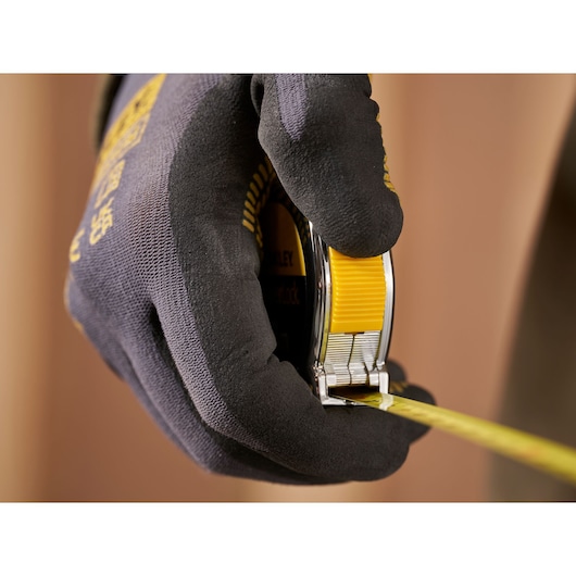 Photo of STANLEY 0-33-238 tape measure in gloved hand, yellow lock button visible, close-up view.
