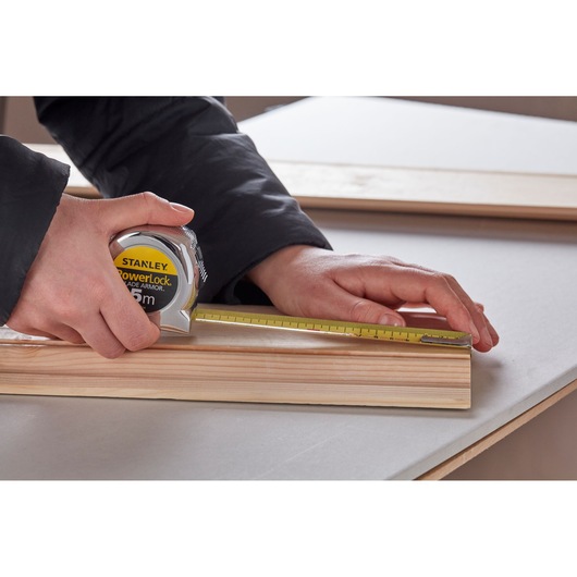 Photo of STANLEY 0-33-514 tape measure being used to measure a wooden board on a table.