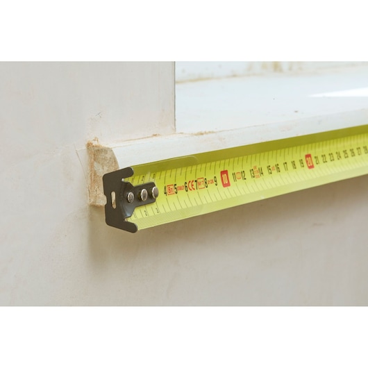 Stanley 0-33-728 tape measure with yellow blade measuring a window ledge, close-up photography.