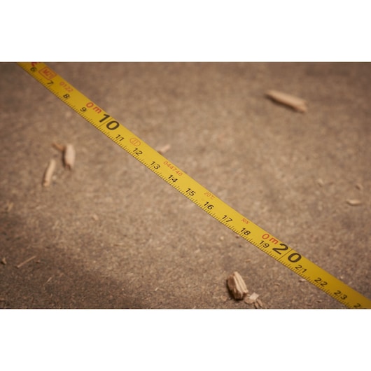 STANLEY 0-34-133 yellow measuring tape with black markings, photography on sandy surface.