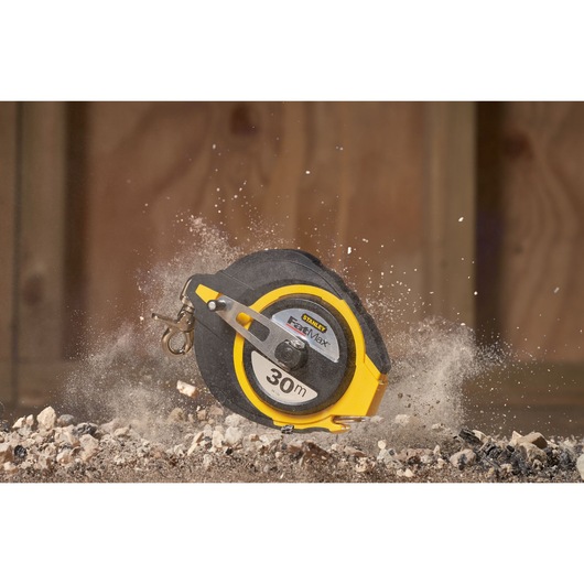 STANLEY 0-34-134 tape measure, 30m, black and yellow case, photographed on construction debris.
