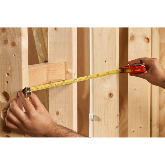 STANLEY 0-34-406 tape measure in use measuring wooden studs, close-up angle.