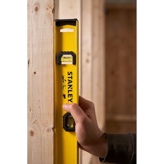 STANLEY 0-42-073 spirit level held vertically against wooden beam, close-up photography.