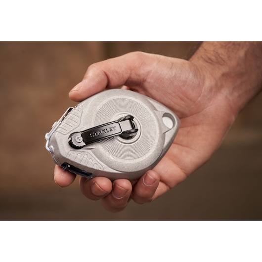 STANLEY 0-47-100 chalk reel in silver, compact oval shape, shown in hand for scale.