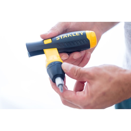 STANLEY 0-63-038 ratcheting screwdriver in black and yellow held in hand, close-up side view.