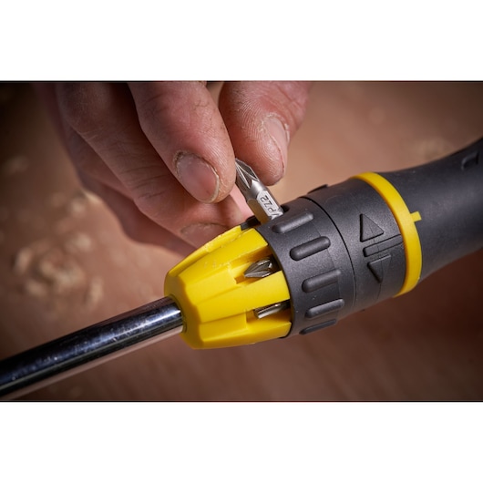 Stanley 0-68-010 screwdriver with yellow and black handle, close-up showing bit selection mechanism in use.