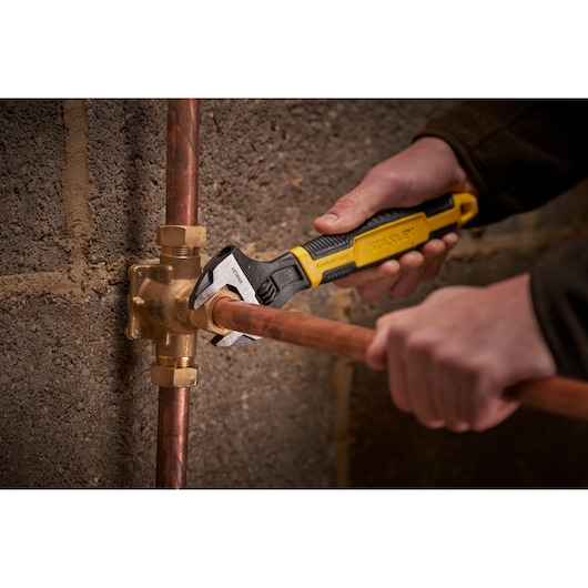 STANLEY 0-90-948 adjustable wrench used on copper pipe fitting, close-up, photography.