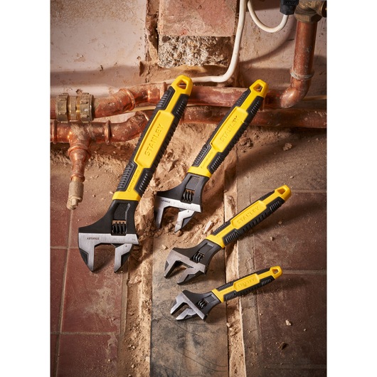 STANLEY 0-90-949 adjustable wrenches set, yellow and black handles, shown at a plumbing worksite.