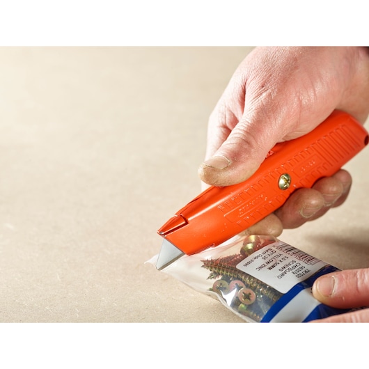 STANLEY 1-10-189 utility knife cutting open a bag of screws, close-up in use.
