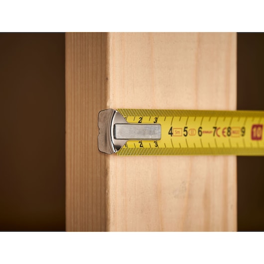 Photo of STANLEY 1-33-195 tape measure measuring a wooden plank, close-up view.