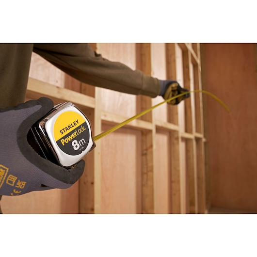 STANLEY 1-33-198 tape measure in use, measuring wooden frame, close-up photography.