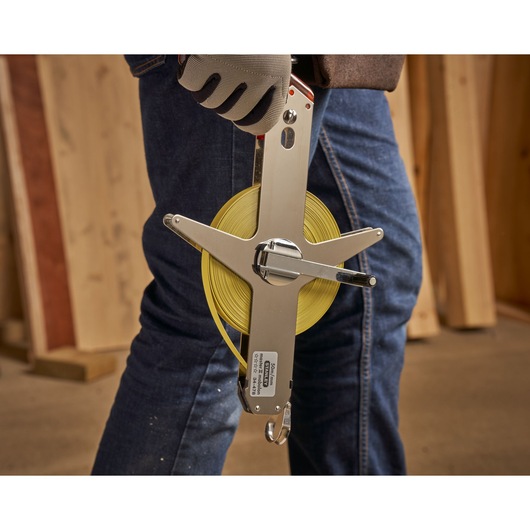 STANLEY 1-34-478 open-frame measuring tape held in hand, yellow blade, construction setting.