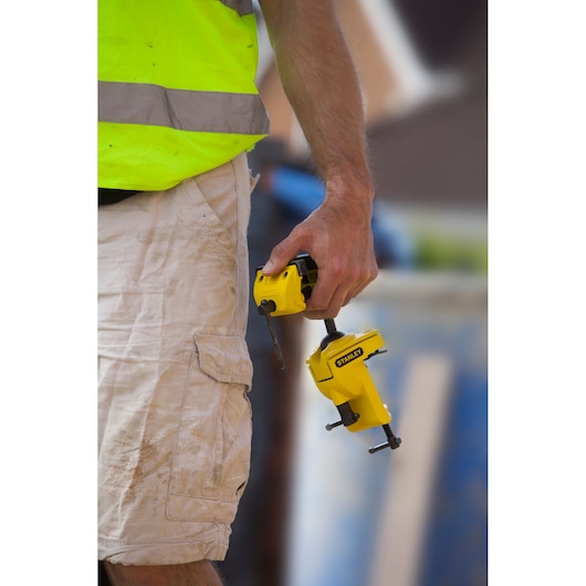 Photo of STANLEY 1-83-069 heavy duty yellow clamp held by worker in beige shorts outdoors.