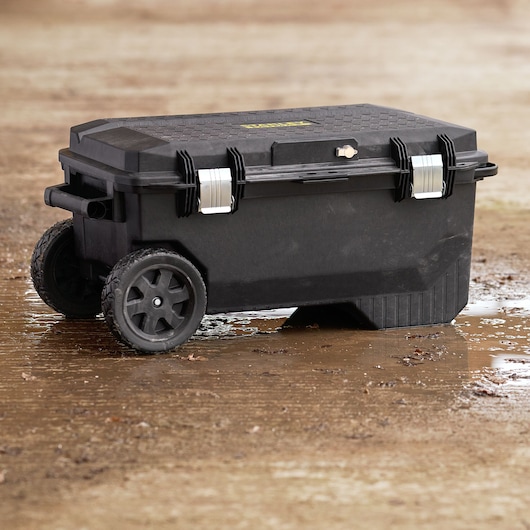 STANLEY 1-94-850 large black rolling toolbox with metal latches on wet outdoor ground, side angle.