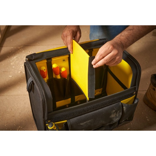 STANLEY 1-97-515 tool bag with yellow interior divider, hand holding divider, front angle.