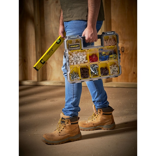 STANLEY 1-97-517 organizer with yellow compartments, held by person with boots, side view photo.