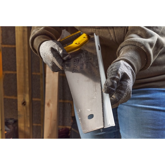 STANLEY 2-15-244 hand saw being used with gloves in a workshop, close-up angle.