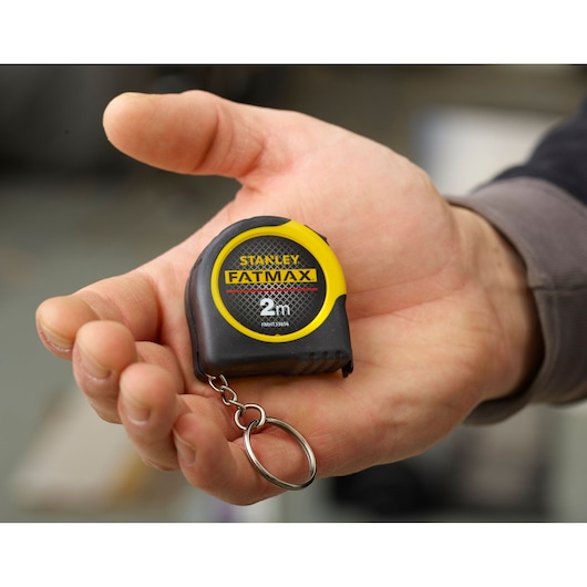 STANLEY FMHT0-33856 FATMAX 2m tape measure keychain held in hand, black and yellow compact design.