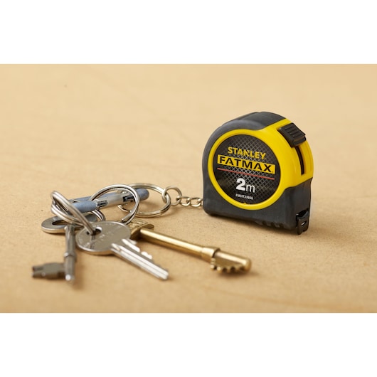 STANLEY FMHT0-33856 FATMAX 2m tape measure keychain in yellow and black beside keys.