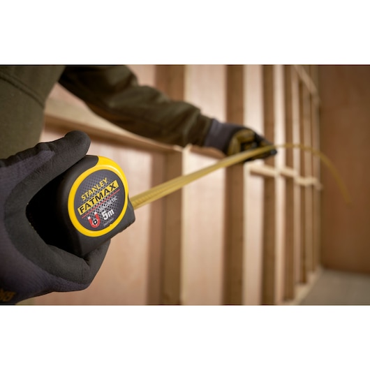 Photo of STANLEY FATMAX tape measure FMHT0-33864 being used to measure a wooden frame.