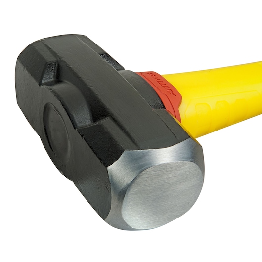 Close-up of a black and silver sledgehammer head with a yellow handle and red accent.