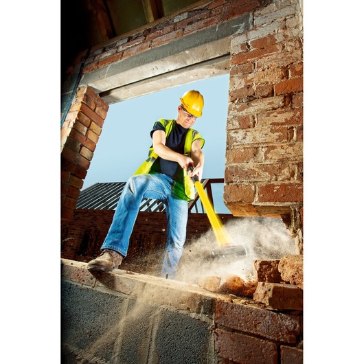 STANLEY FMHT1-56011 sledgehammer in use breaking a brick wall on a construction site, action photography.