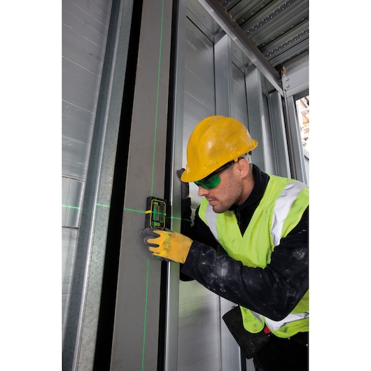 STANLEY FMHT1-74267 laser level in use on metal frame by worker in yellow helmet and vest, construction site.