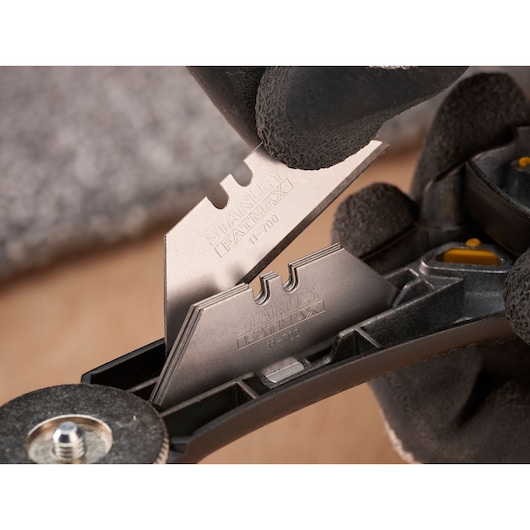 STANLEY FMHT10500-0 utility blades being handled and stored in black holder, close-up photography.