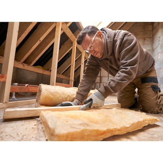 STANLEY FMHT10501-0 utility knife cutting insulation material in attic, close-up photo of tool in use.