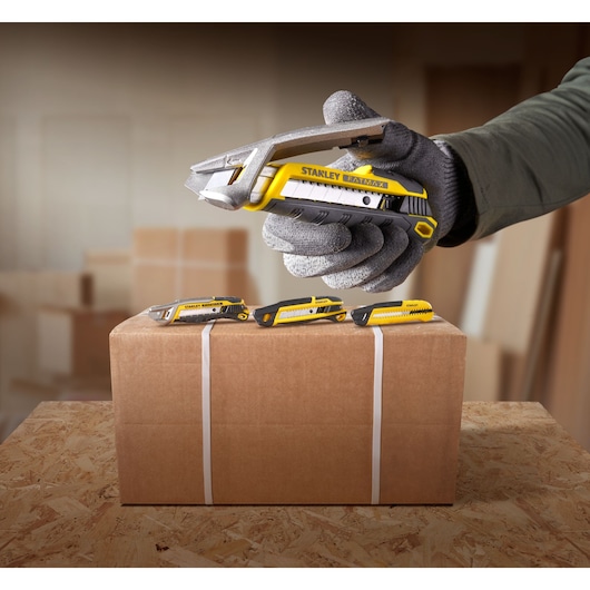 STANLEY FMHT10594-0 utility knife cutting box tape, three knives on top, yellow and black handle.