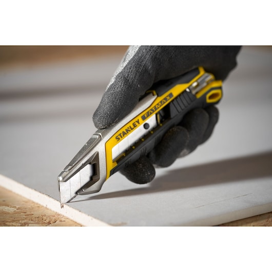 Photo of STANLEY FMHT10594-0 utility knife with yellow and black handle cutting drywall.