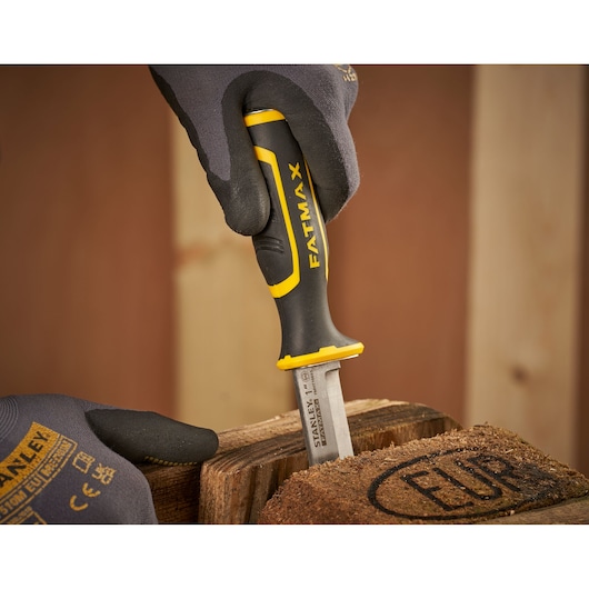 STANLEY FMHT16693-0 chisel with black and yellow FATMAX handle in use on wood surface, close-up.