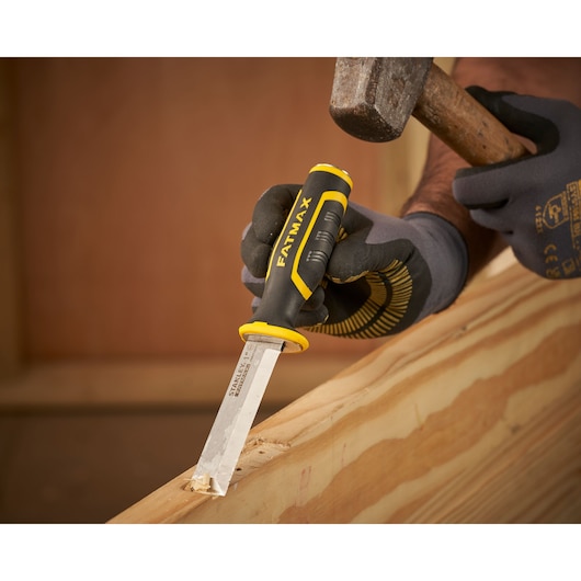 Photo of STANLEY FMHT16693-0 chisel with black and yellow handle being used on wood with gloves.
