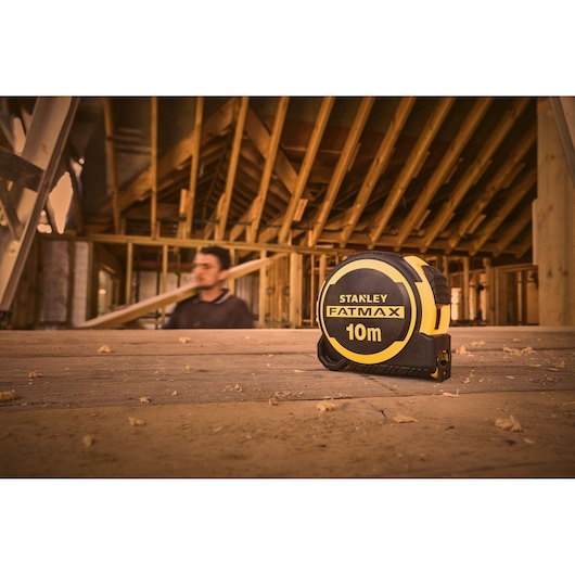 STANLEY FATMAX 10m tape measure, SKU FMHT33005-0, on wooden floor at construction site.