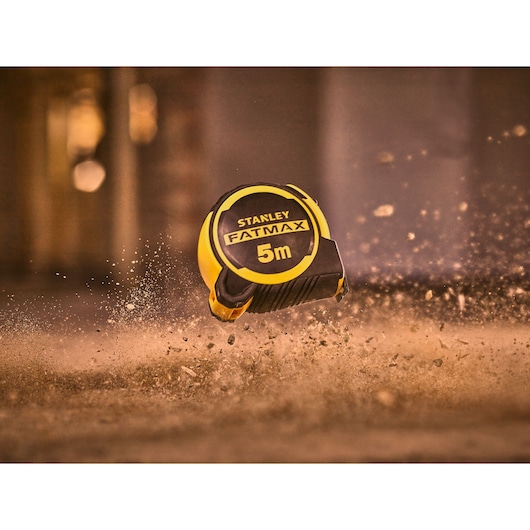 STANLEY FMHT33100-0 tape measure FATMAX 5m in black and yellow, photographed in dusty environment.