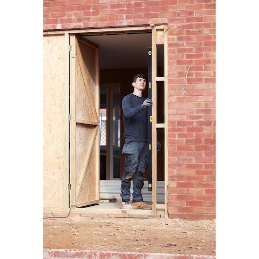 Photo of worker using STANLEY FMHT42561-1 spirit level at door frame construction site.