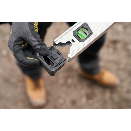 STANLEY FMHT43670-1 digital level being held by a gloved hand outdoors, close-up view.