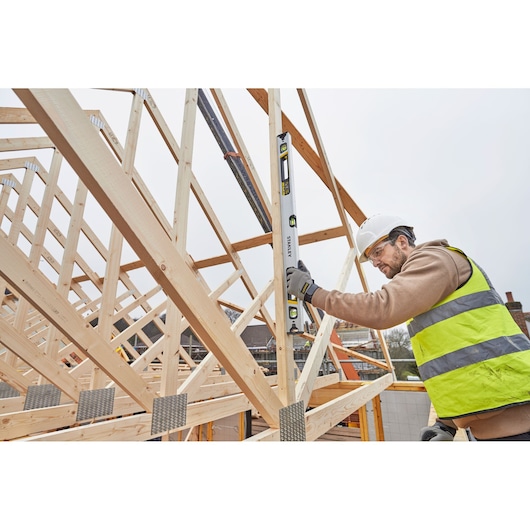 STANLEY FMHT43674-1 spirit level used by worker on timber roof frame at construction site.