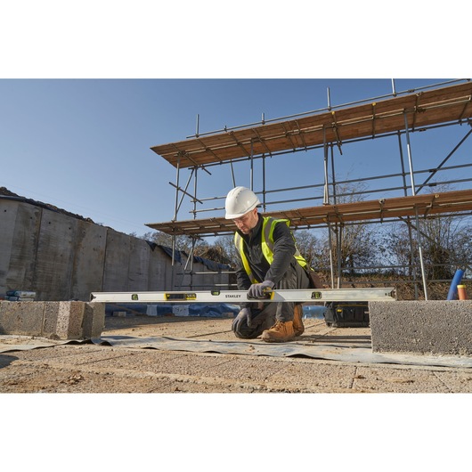 STANLEY FMHT43678-1 spirit level used by worker in safety gear on construction site, outdoor scene.