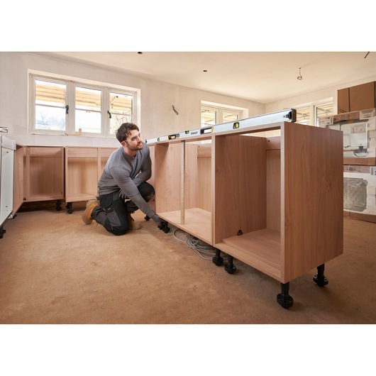 STANLEY FMHT43678-1 spirit level on wooden kitchen cabinet during installation, wide angle.