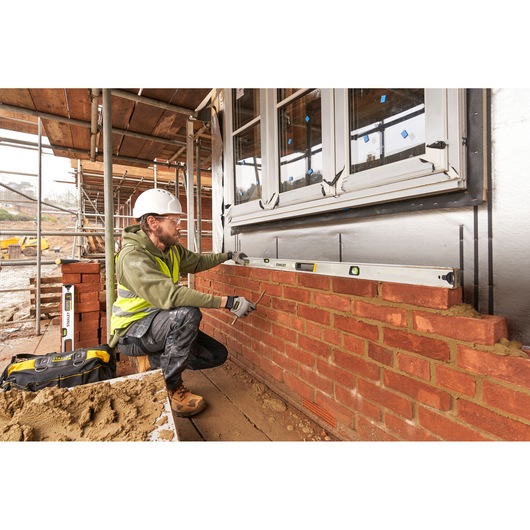 Photo of STANLEY FMHT43680-1 spirit level used by a worker aligning bricks on a construction site.