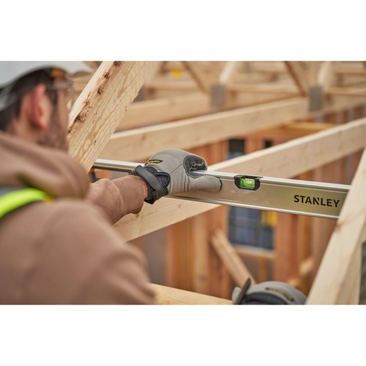 Stanley FMHT43680-1 spirit level used by worker in construction, focusing on level tool and wooden frame.