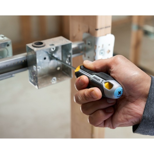 Hand using Stanley screwdriver to fasten screw in metal electrical box during installation.